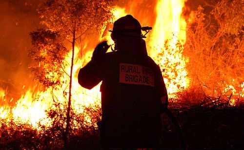 A rural fire Brigade officer watches flames inch closer to homes in the Kin Kin area. A rural fire Brigade officer watches flames inch closer to homes in the Kin Kin area.